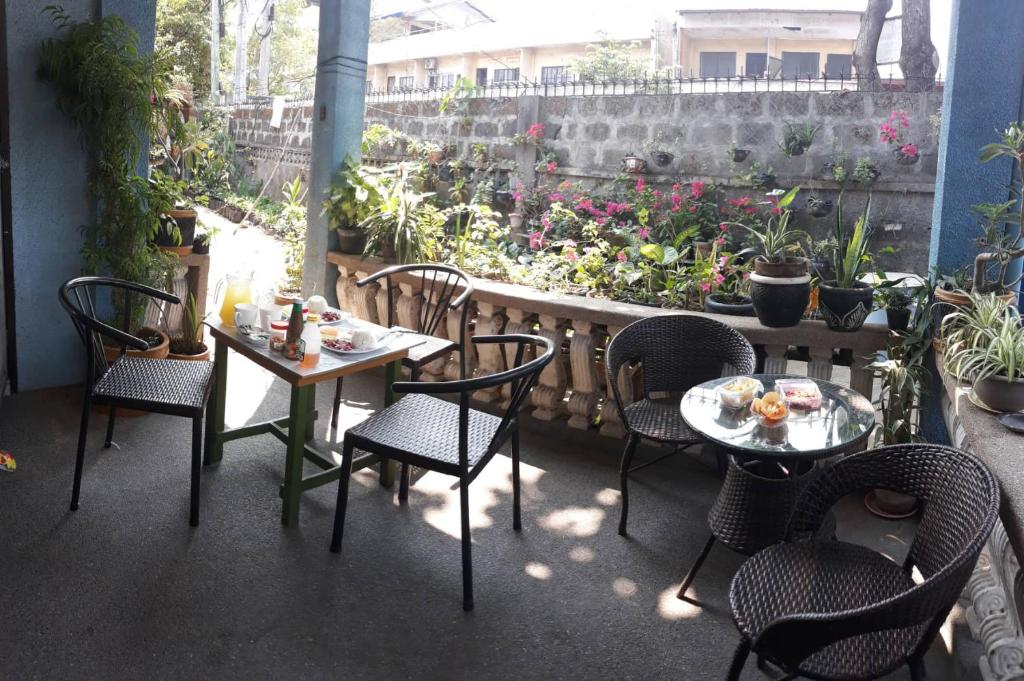 a patio with tables and chairs and a garden at cv bed n bath san juan in Dalumpinas Oeste