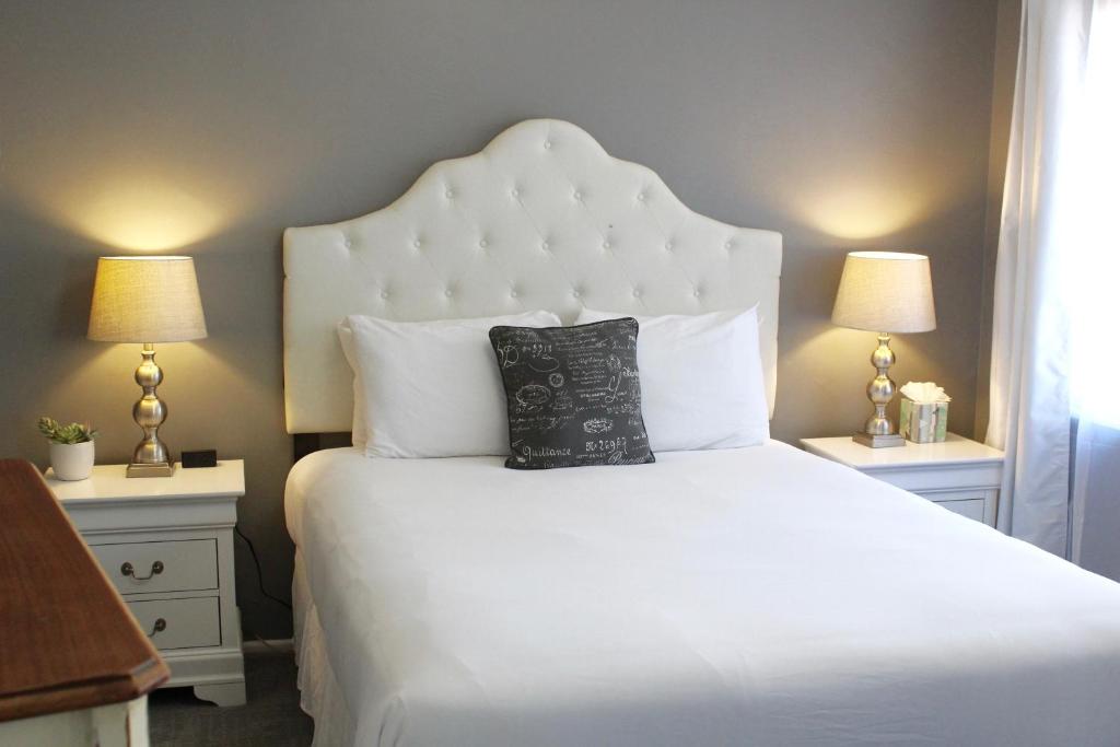 a bedroom with a white bed with two night stands at New Haven Inn in Solvang