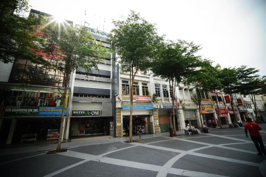een lege straat met bomen en gebouwen bij Hotel A-One in Kuala Lumpur
