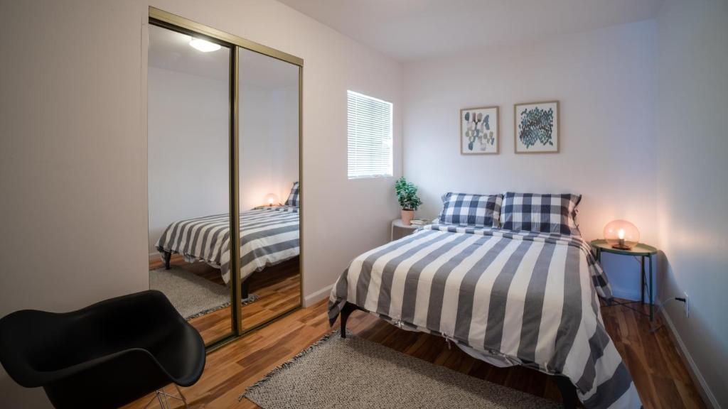 a bedroom with a mirror and a bed and a chair at Charming 2BR Casita in Front of Park in Los Angeles