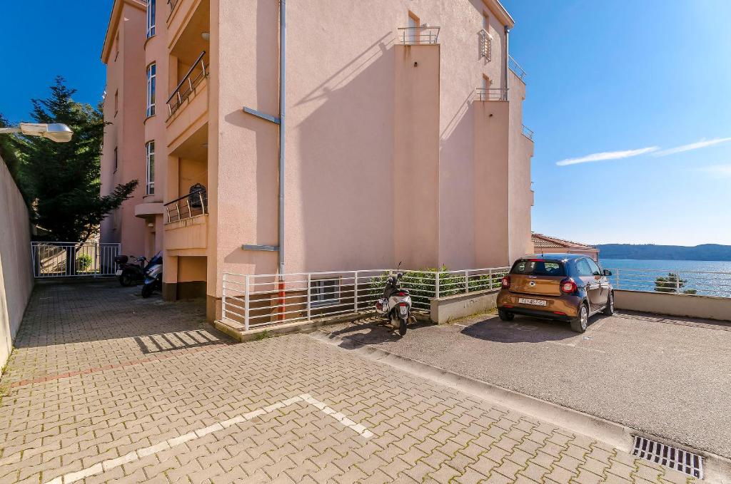 une moto garée à côté d'un bâtiment à côté de l'eau dans l'établissement Apartment Mia, à Trogir