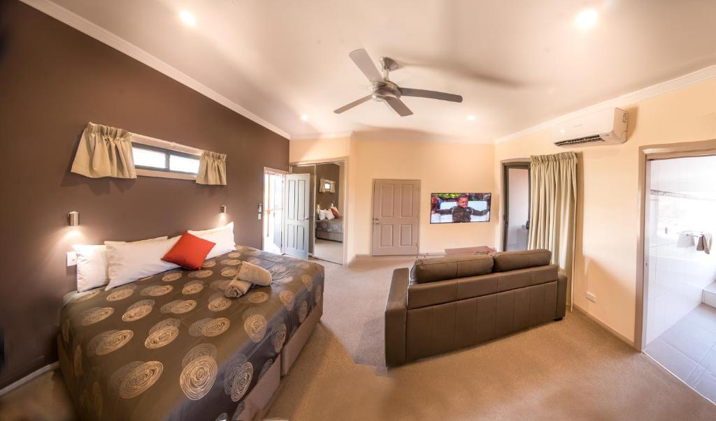 um quarto com uma cama, um sofá e uma ventoinha de tecto em Broken Hill Outback Resort em Broken Hill
