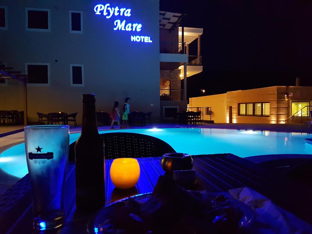 eine Flasche Wein und ein Glas neben einem Swimmingpool in der Unterkunft Plytra Mare Hotel in Plitra