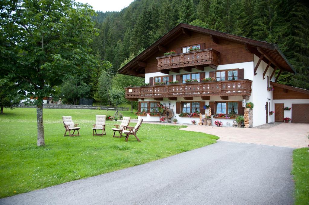 ein Haus mit Stühlen im Gras davor in der Unterkunft Landhaus Manuela & Haus Michael in Leutasch