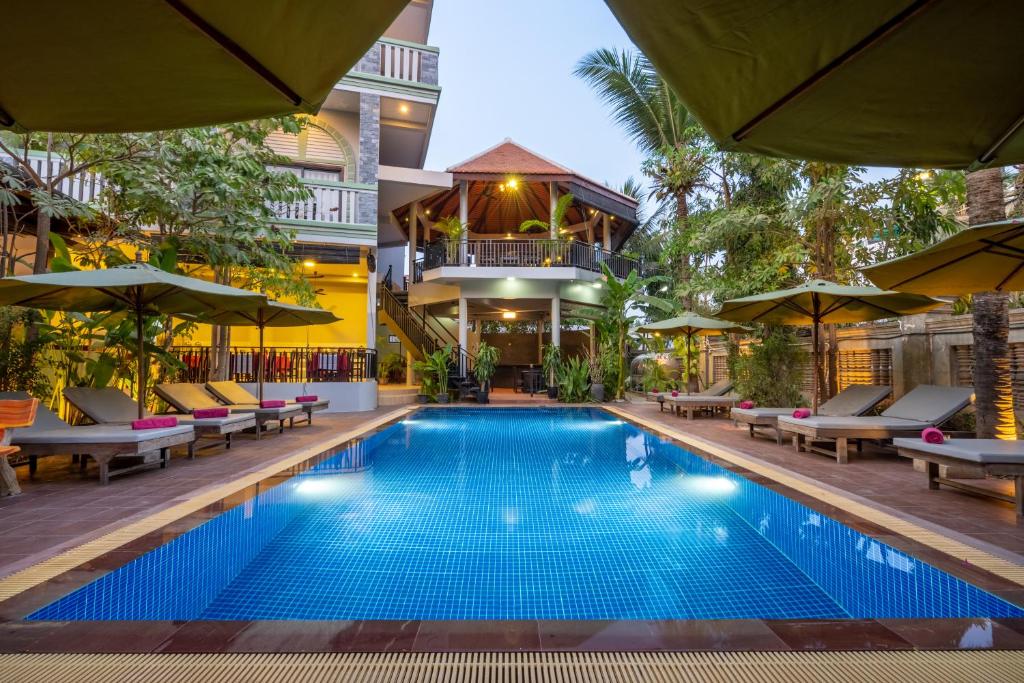 una piscina en un hotel con sillas y sombrillas en Reveal Courtyard in Reveal Angkor en Siem Riep