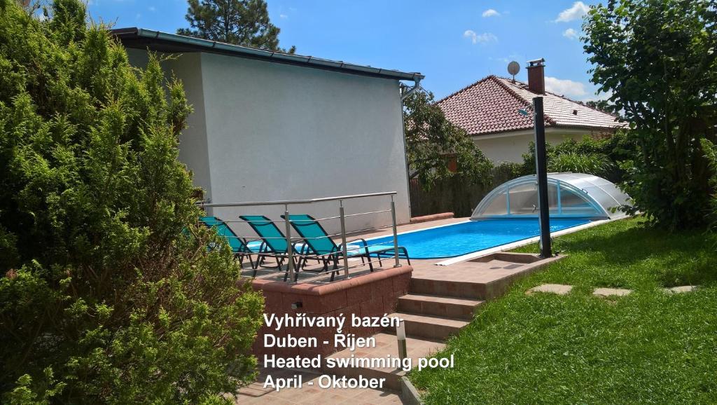a swimming pool with chairs next to a house at Penzion Kalina in Tábor