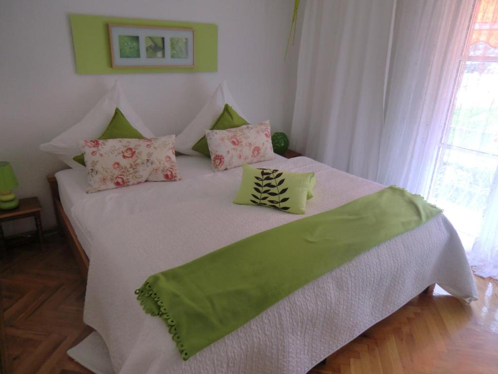 Un dormitorio con una cama blanca con almohadas verdes y rosas en Haus Marija M en Badenweiler