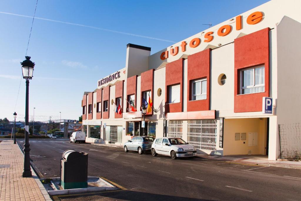 un edificio con coches aparcados fuera de él en una calle en Aparthotel Autosole, en Estepona