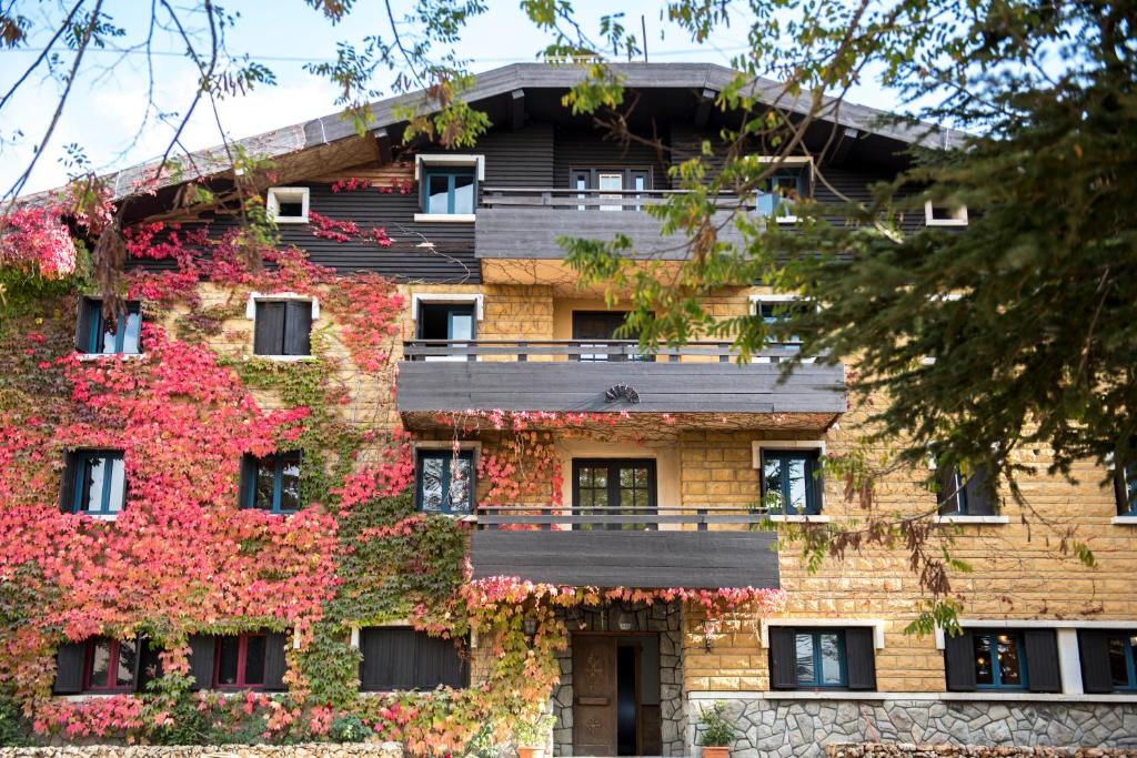 um edifício coberto de heras e flores em La Maison des Cèdres em Al Arz