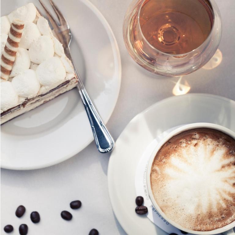 Overhead view of coffee cup, glass, and marshmallow-topped dessert on a white table.