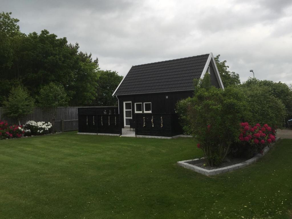 a small black house with a green yard at Skagen anneks in Skagen