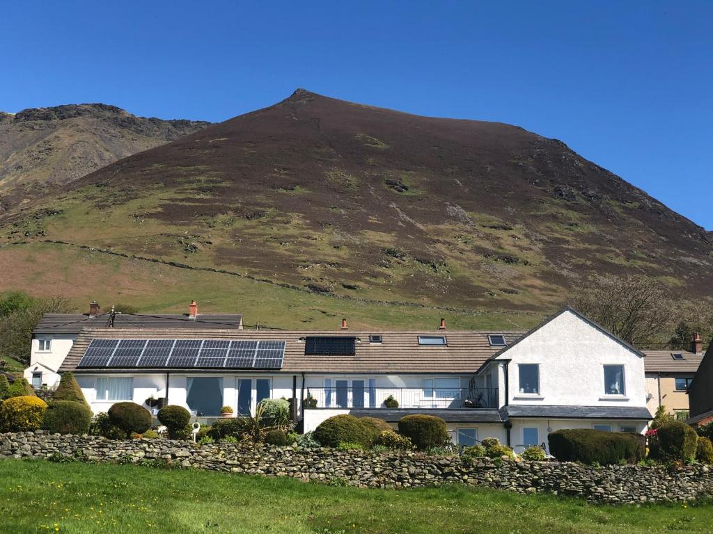uma casa com painéis solares em frente a uma montanha em The Bungalows Guesthouse em Threlkeld