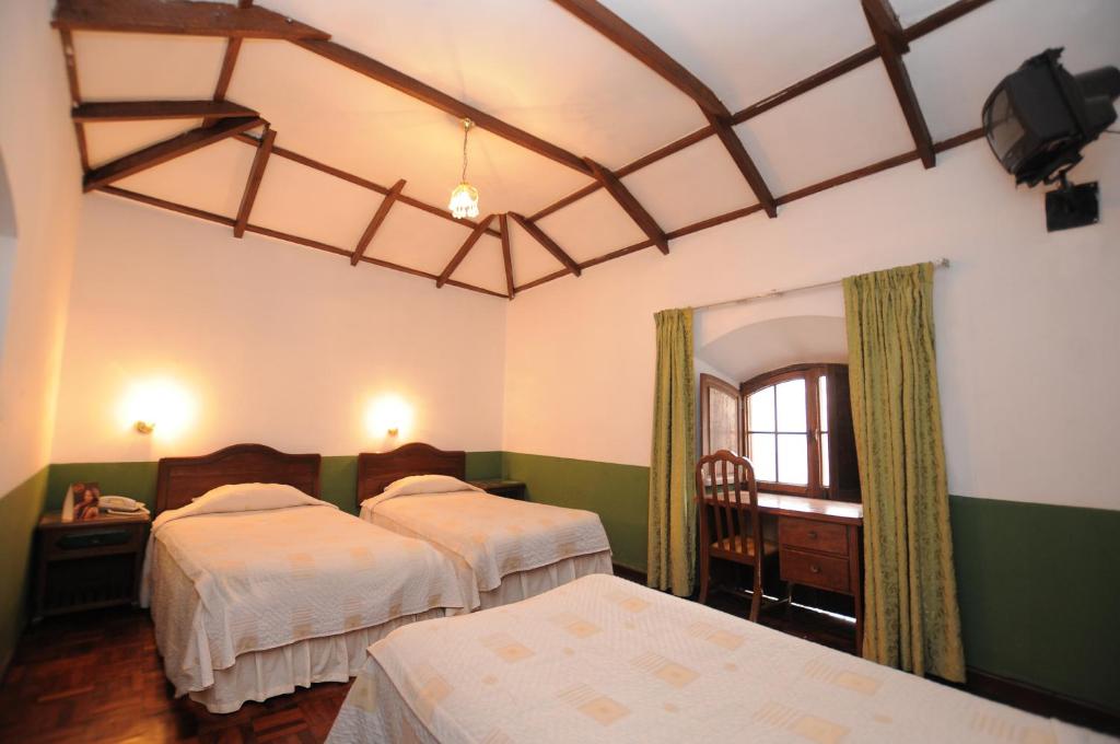 1 dormitorio con 2 camas y espejo en Hostal Recoleta Sur, en Sucre