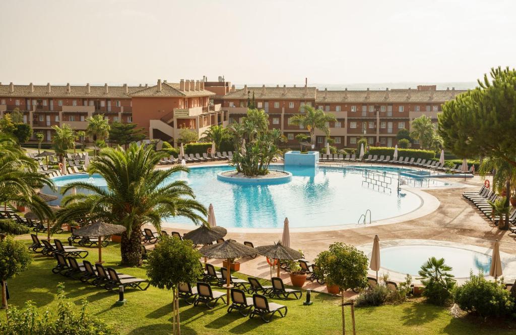 ein Bild eines Resortpools mit Stühlen und Bäumen in der Unterkunft Ilunion Sancti Petri in Chiclana de la Frontera