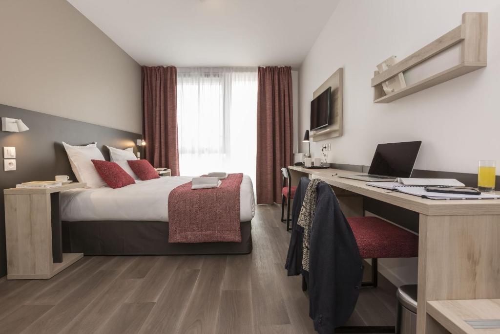 una camera d'albergo con letto e scrivania di Odalys City Le Mans Centre Congrès a Le Mans