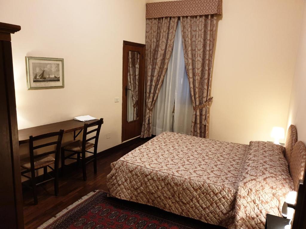 sypialnia z łóżkiem, stołem i biurkiem w obiekcie Affittacamere Mazzini 78 w mieście Grosseto