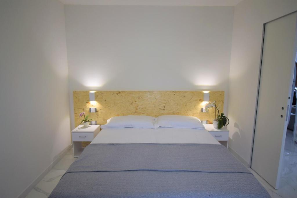 una camera da letto con un grande letto bianco con due tavoli bianchi di Uni Apart a Trento