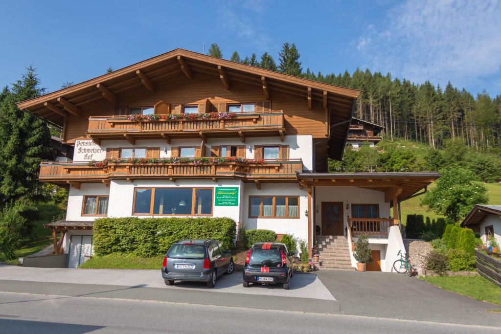 una casa con dos coches estacionados frente a ella en Pension Schweizerhof, en Waidring