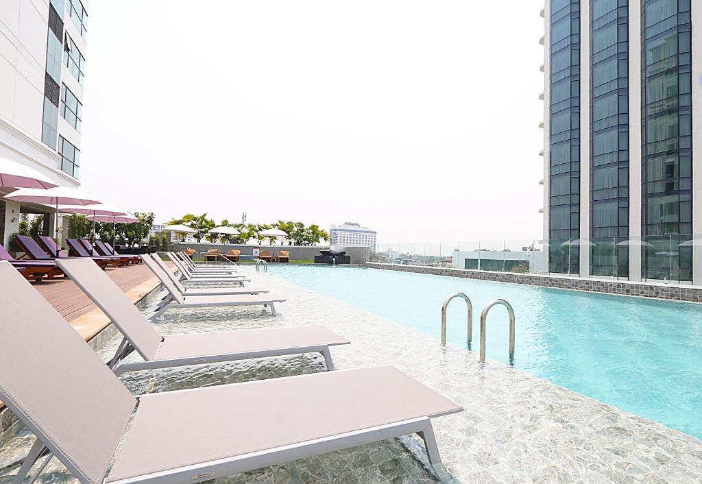 A rooftop pool deck with loungers, umbrellas, and a city-facing edge.