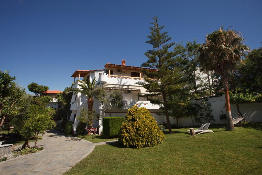 een groot wit gebouw met bomen en een gazon bij Castello Verde Apartments Studios in Plakias