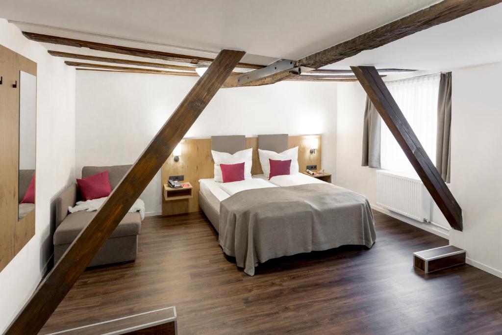 a bedroom with a bed with red pillows and a couch at Hotel & Restaurant Lamm in Mosbach