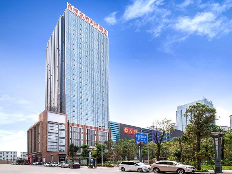 PuningにあるVienna International Hotel Guangdong Puning Sqaureの前に車が駐車されている高い建物
