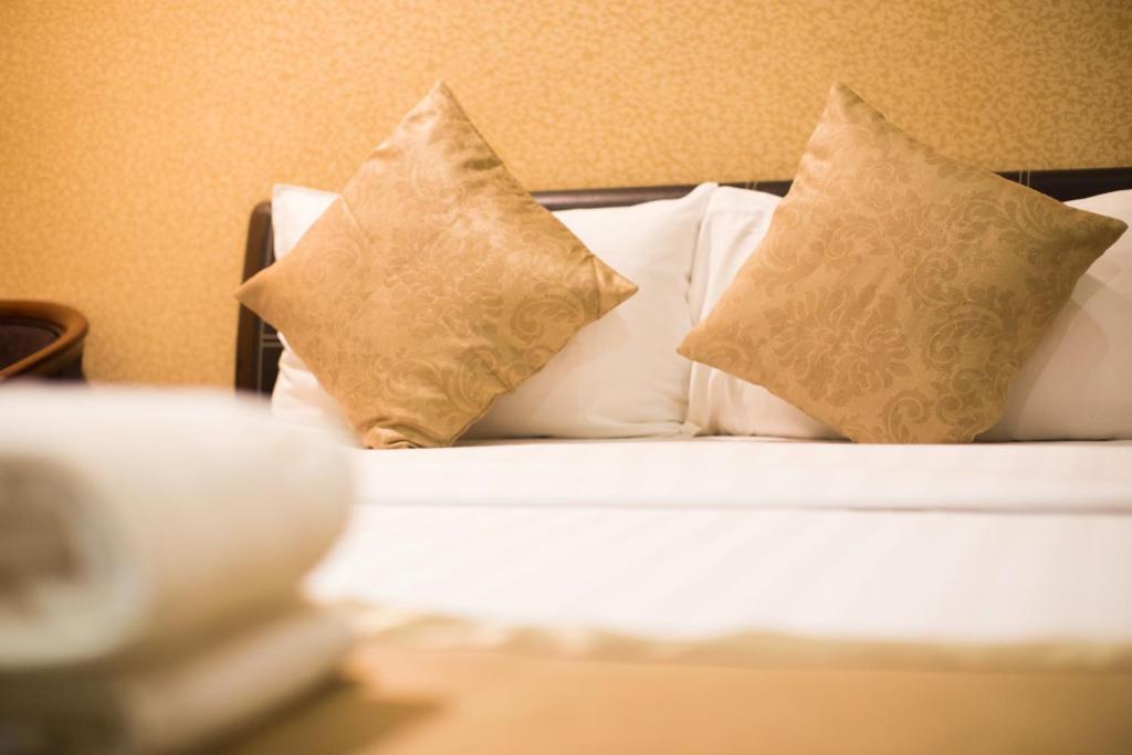 una cama con almohadas en una habitación en Hotel Valenza, en Kuala Lumpur