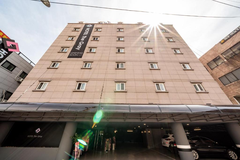 un edificio alto e marrone chiaro con un cartello sopra di THE GRAY HOTEL a Seul