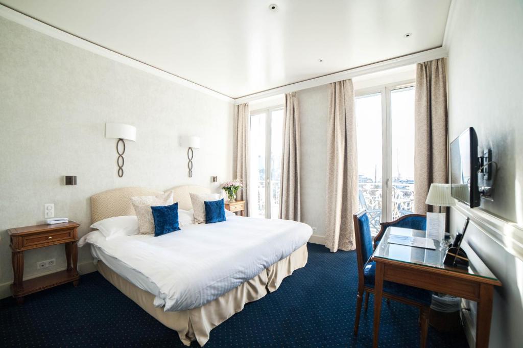 a hotel room with a bed and a desk and window at Hotel Splendid in Cannes