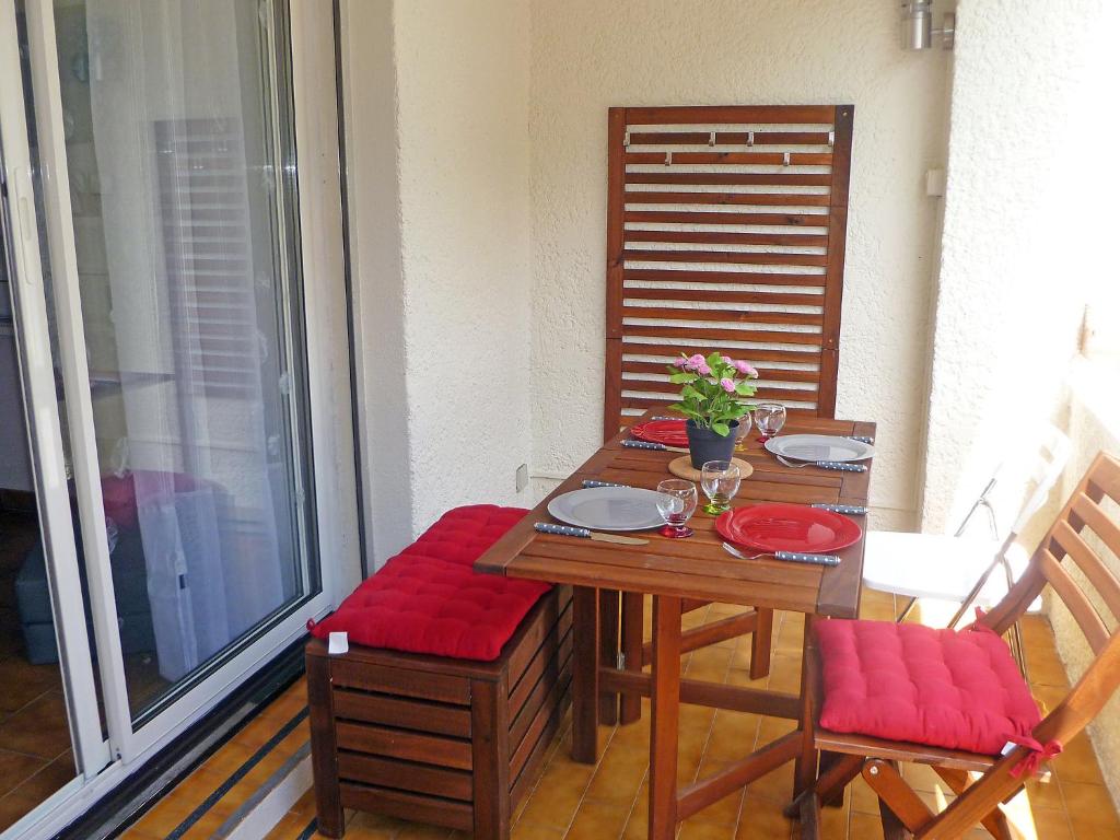 uma mesa de madeira com almofadas vermelhas numa varanda em Apartment L'Ile heureuse-6 by Interhome em Saint-Cyr-sur-Mer