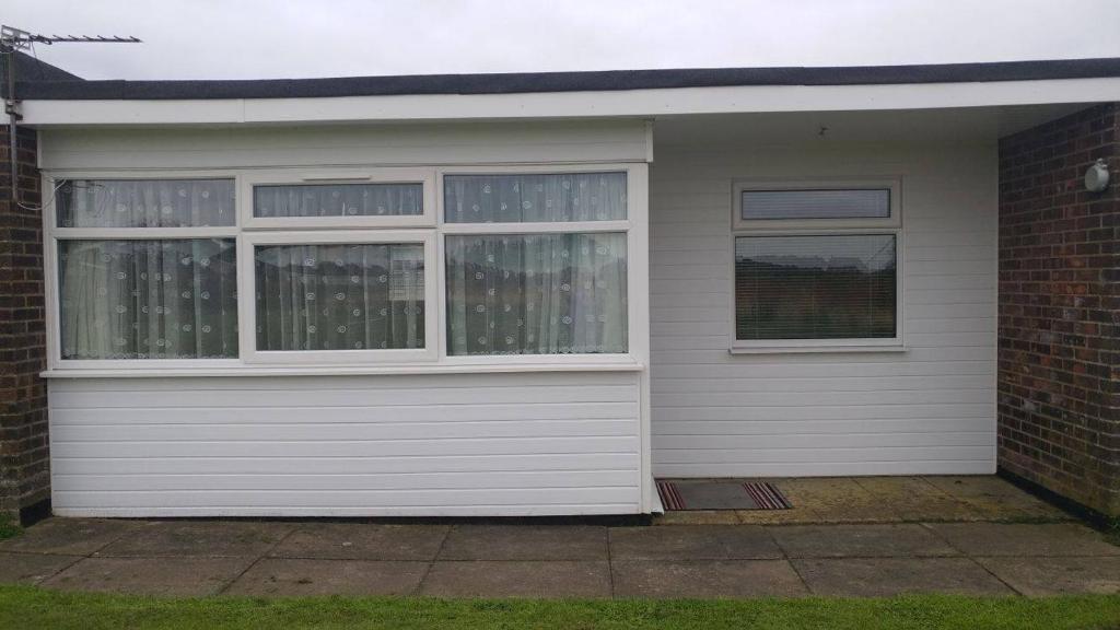 uma garagem branca com duas janelas e uma casa de tijolos em alicias chalets em Great Yarmouth