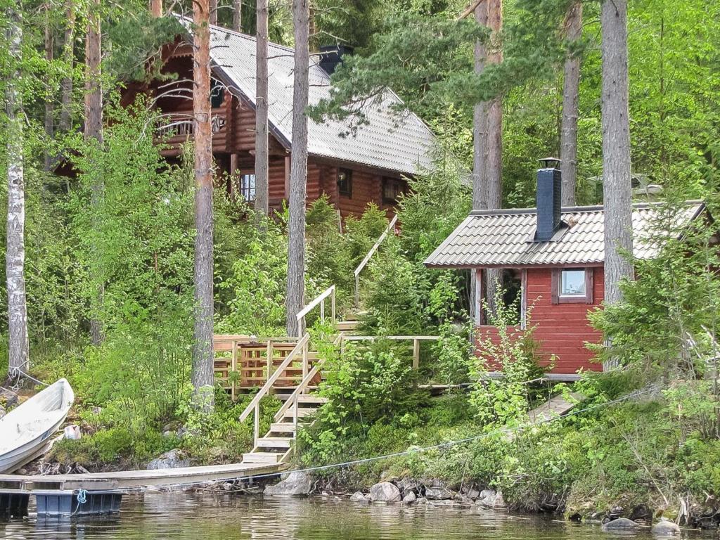 a cabin on the side of a river with a boat at Holiday Home Iltarusko by Interhome in Vuoriniemi