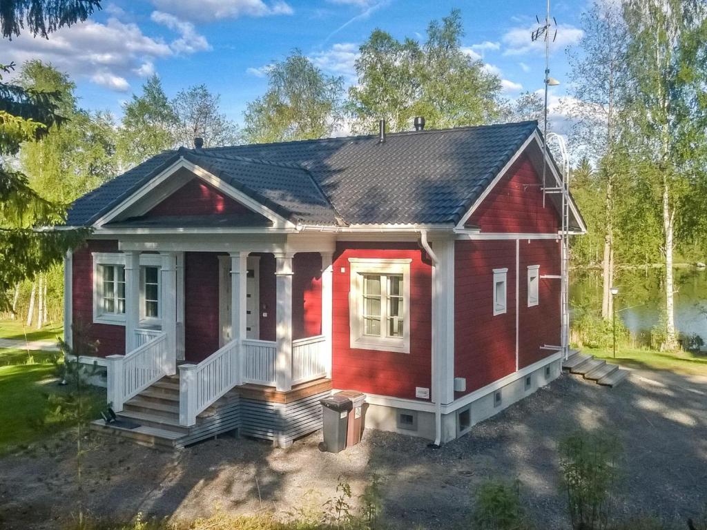 uma casa vermelha com um alpendre branco em Holiday Home Villa urho by Interhome em Löytö