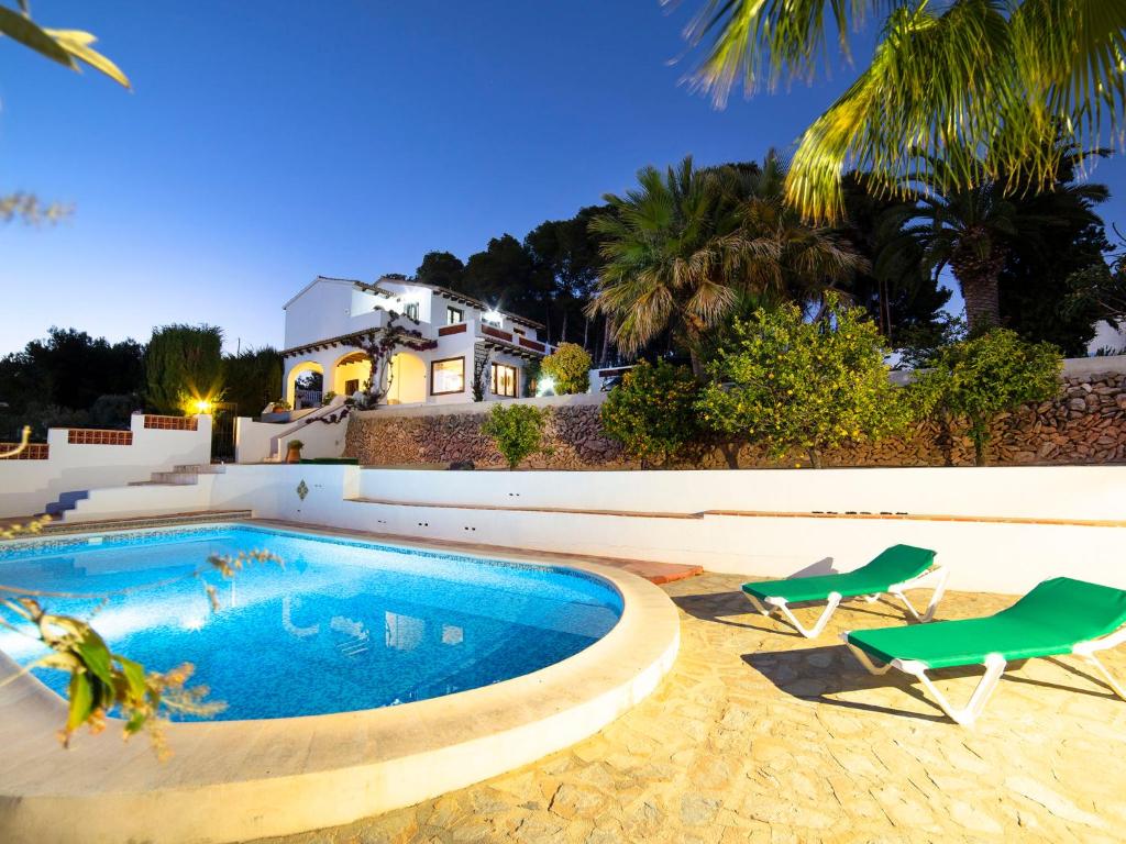 a swimming pool with two chairs and a house at Villa La Mancha by Interhome in Benissa