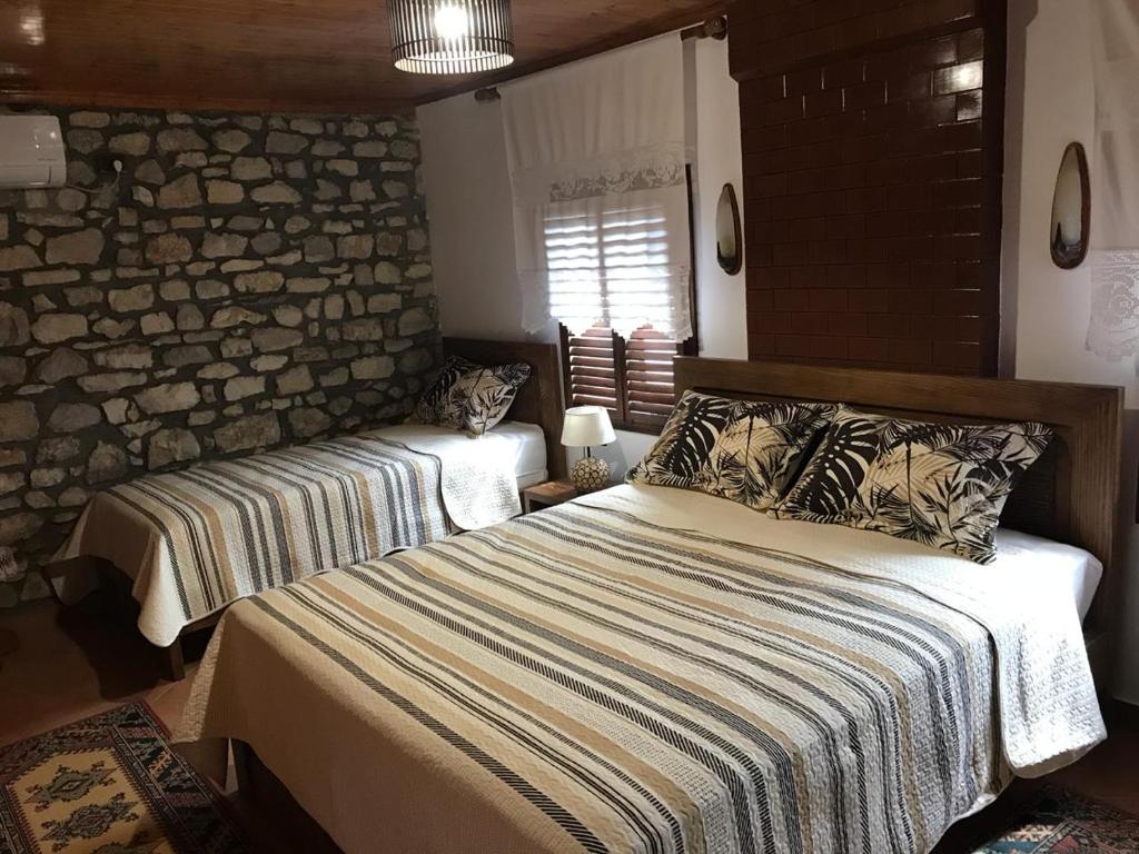 a bedroom with two beds and a stone wall at Guesthouse Arjan in Berat