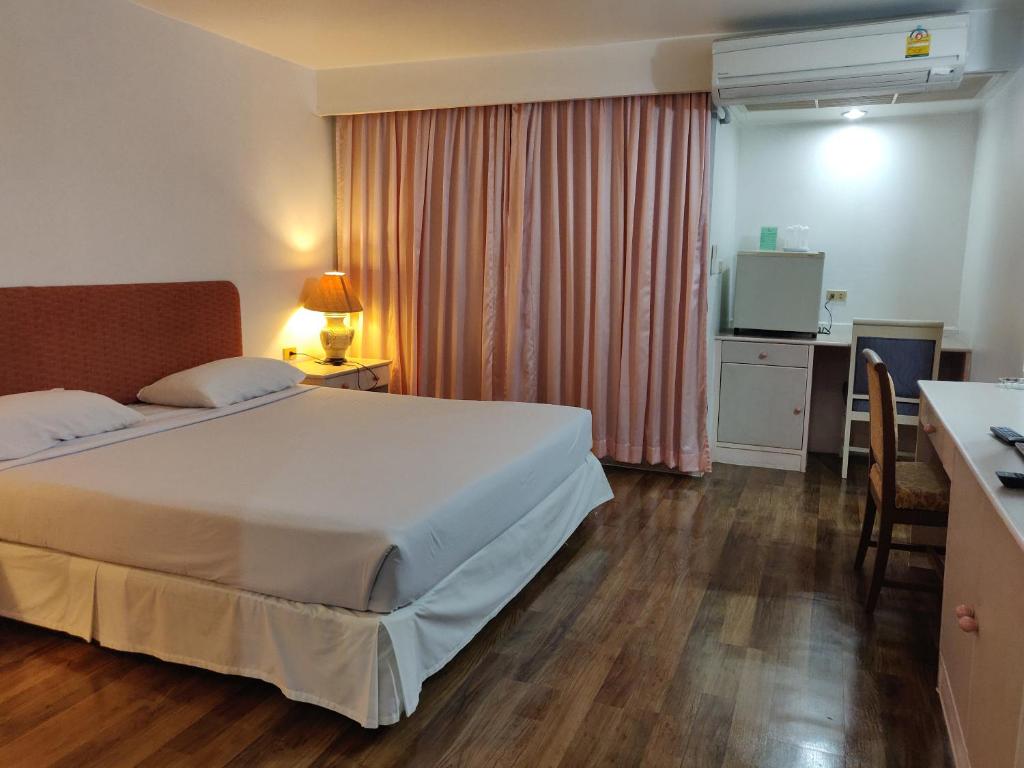 a hotel room with a large bed and a desk at LEE PLACE HOTEL in Bangkok