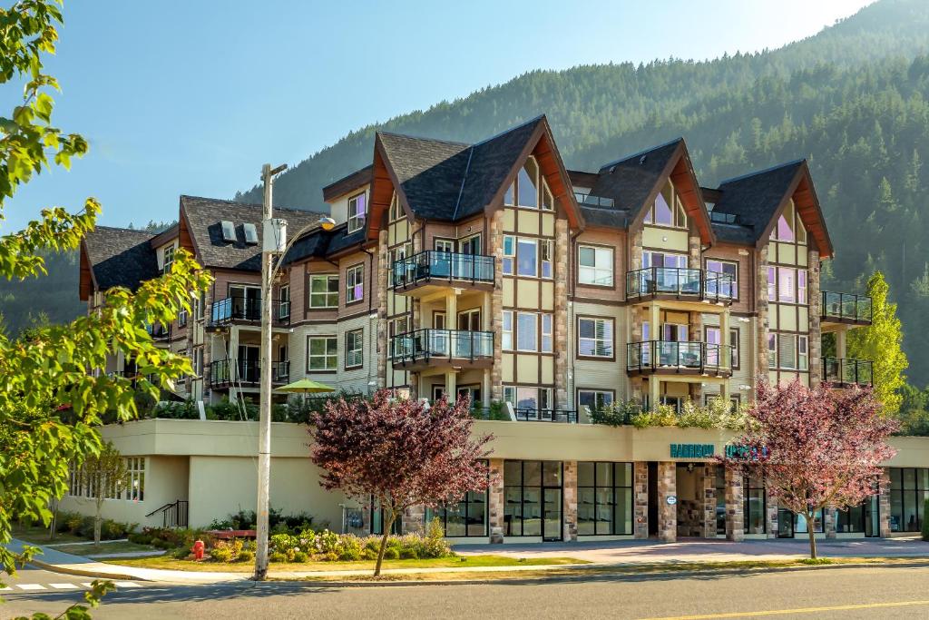a large apartment building with mountains in the background at Harrison Lake View Suites in Harrison Hot Springs