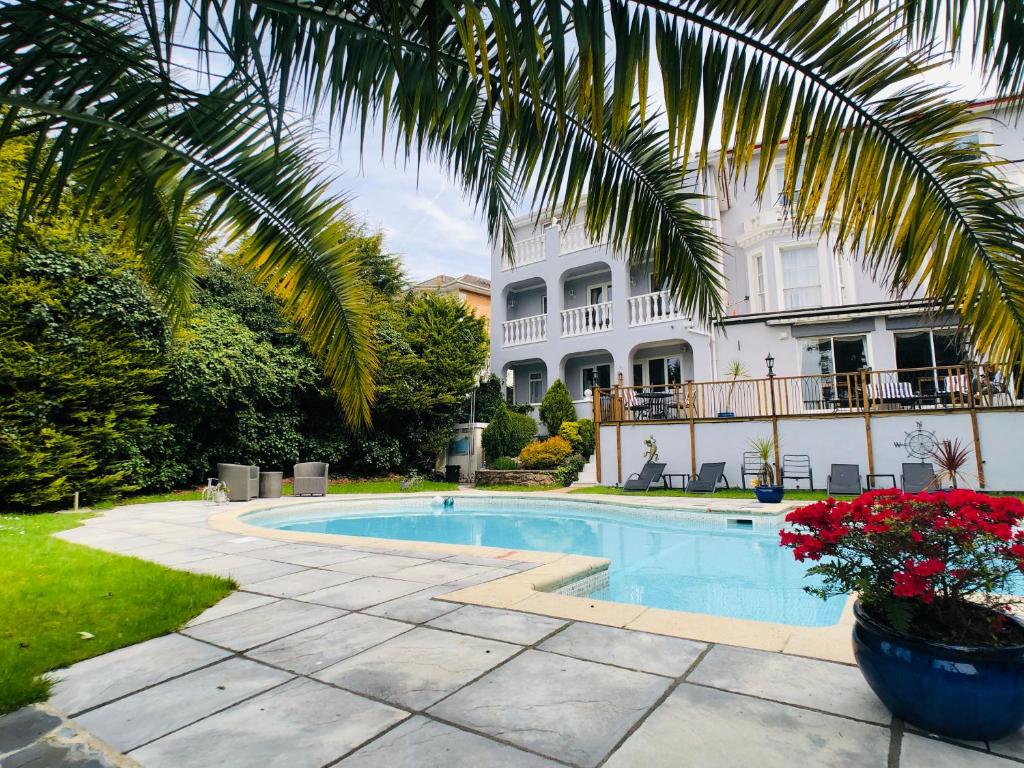 a swimming pool in front of a house with a palm tree at Glenorleigh in Torquay