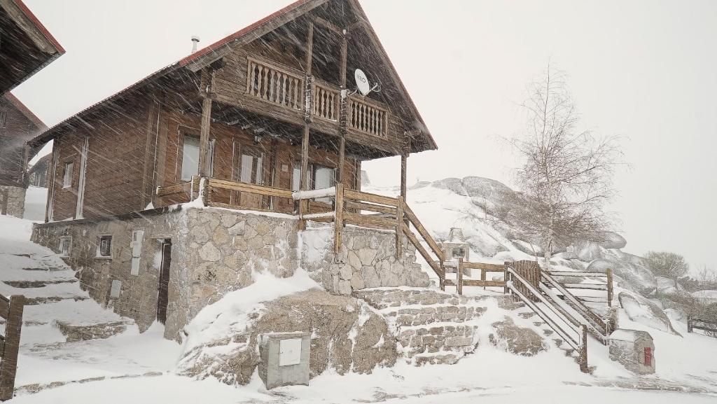 uma cabana de madeira na neve com uma cobertura de neve em Chalé | Penhas da Saúde - Serra da Estrela em Penhas da Saúde