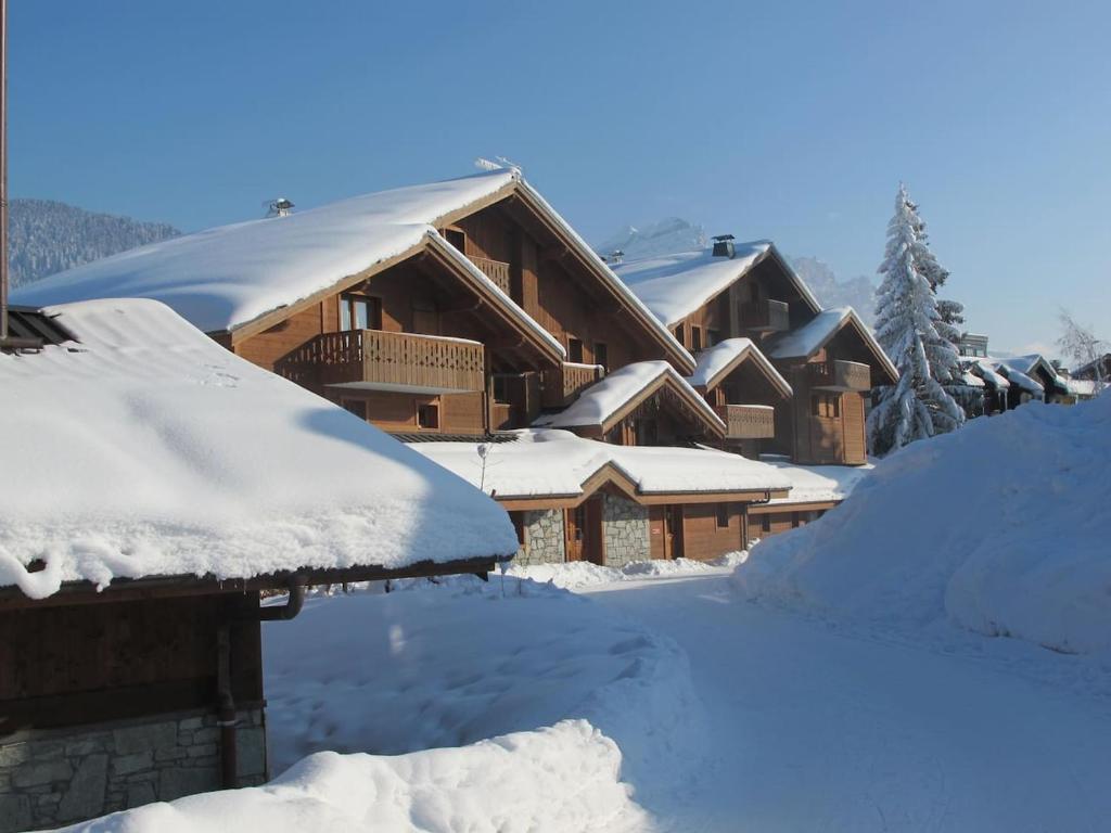 uma casa coberta de neve com telhados cobertos de neve em Chalet Les Trappeurs em Les Carroz d'Arâches