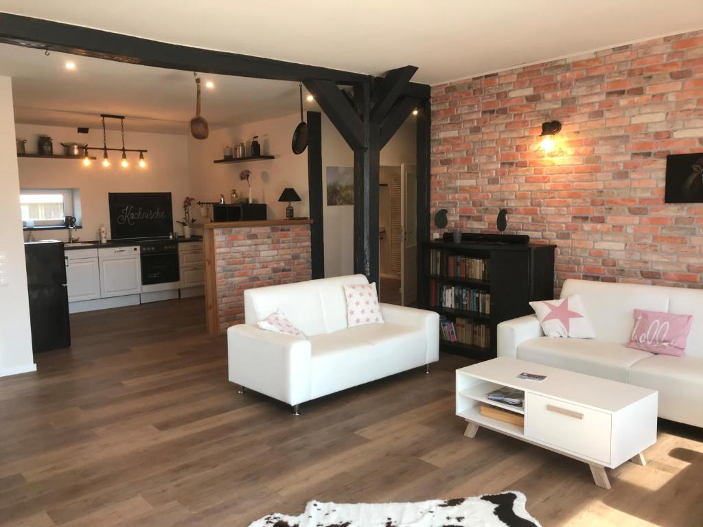 a living room with two white couches and a brick wall at HeideZeit 3 in Neuenkirchen