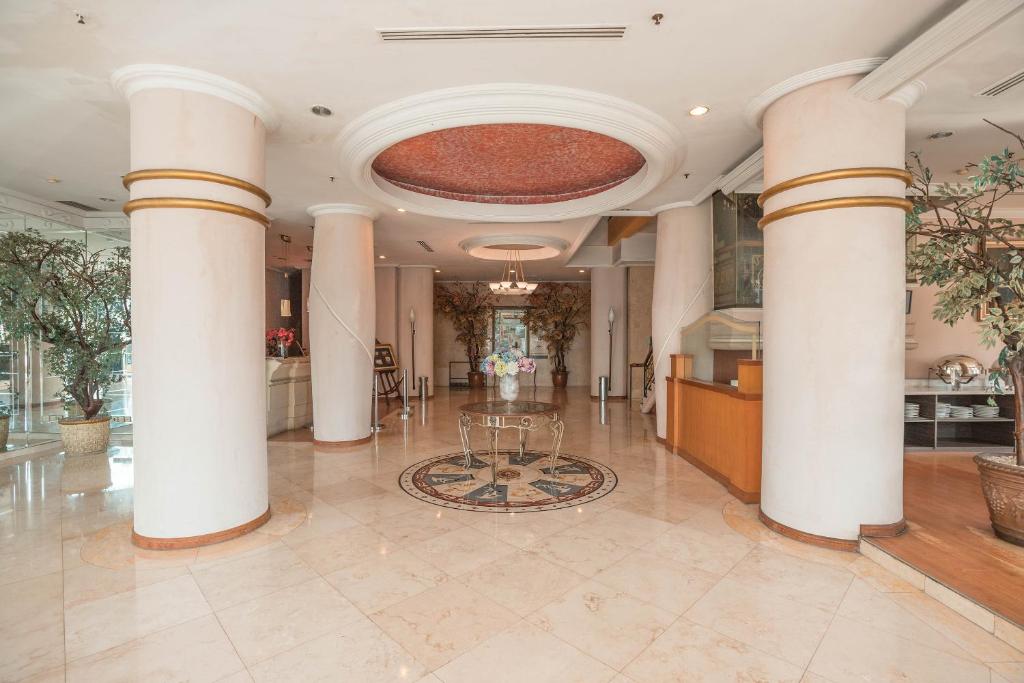a lobby with columns and a table in the middle at Hotel Bulevar Tanjung Duren Jakarta in Jakarta