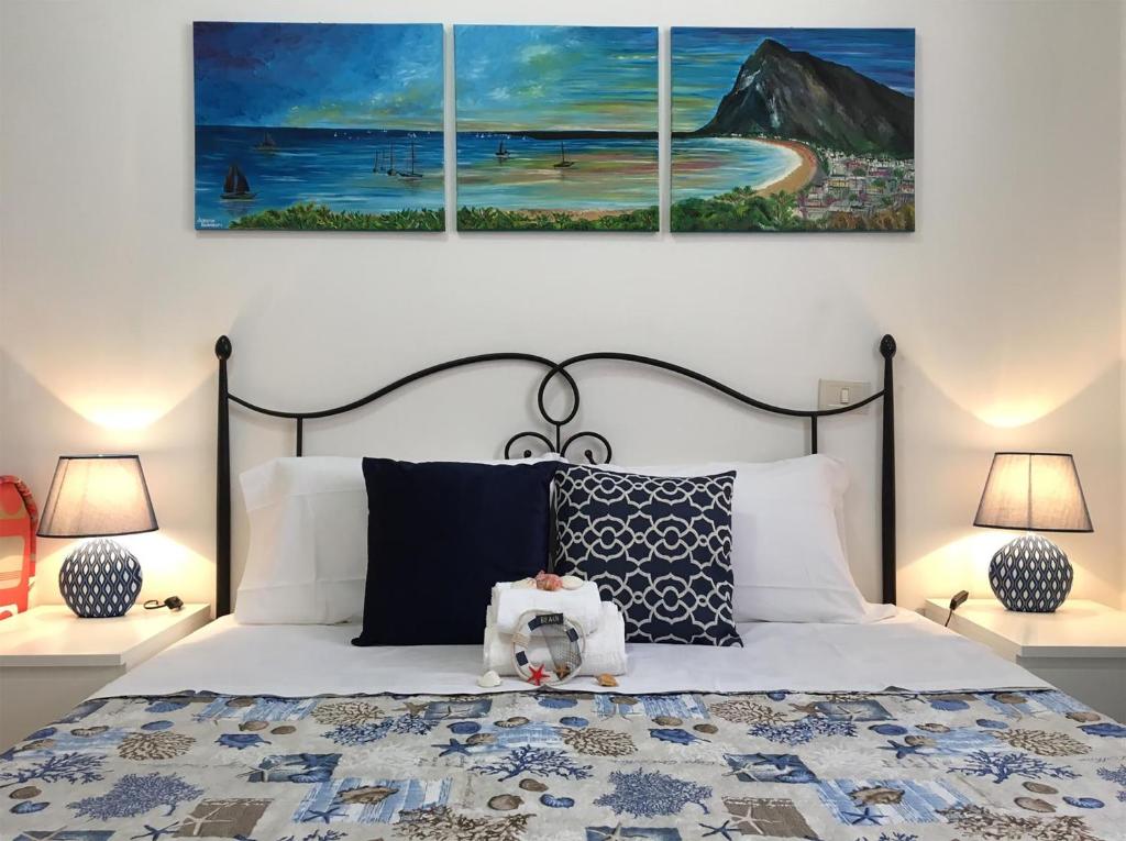 a bedroom with a bed with three paintings on the wall at Appartamenti Monacò in San Vito lo Capo