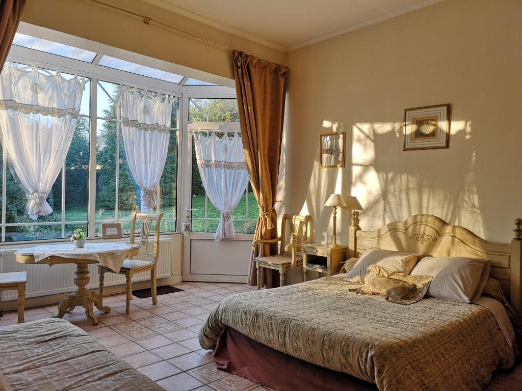 a bedroom with a bed and a table and a window at Le Domaine des Prés du Hom in Bézu-Saint-Éloi