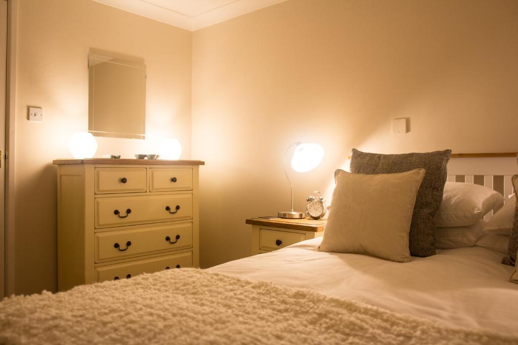 a bedroom with a bed and a dresser with two lights at Shaftesbury Modern Annexe in Shaftesbury