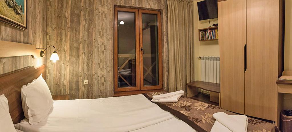 um quarto com uma grande cama branca e uma janela em Family Hotel Balkanci em Uzana