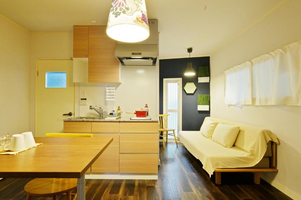 een woonkamer en een keuken met een bank en een tafel bij Konpeito House in Osaka