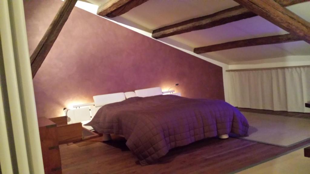 1 dormitorio con 1 cama con paredes moradas y suelo de madera en B&B Palazzo Regaù, en Vicenza