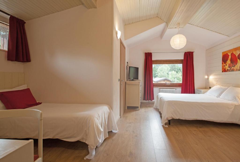 1 dormitorio con 2 camas y ventana en Hotel Prealpi, en Castione della Presolana