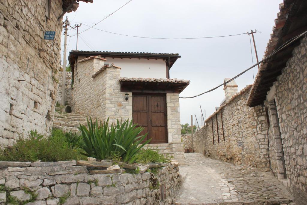 an alley with a wooden door in a stone building at Guesthouse Arjan in Berat